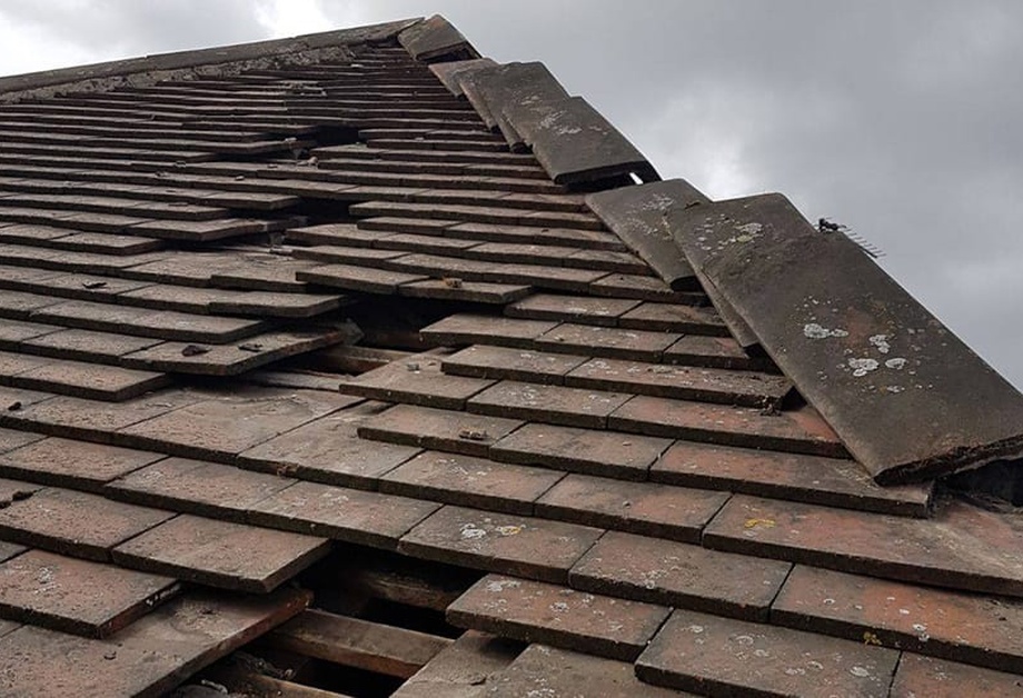 Roof repair or replacement Limerick showing professional roofer inspecting damaged roof tiles